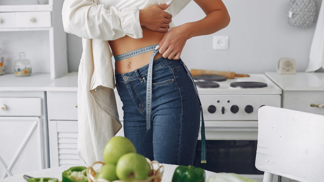 A woman measuring her tummy after losing her weight through Keto fasting 