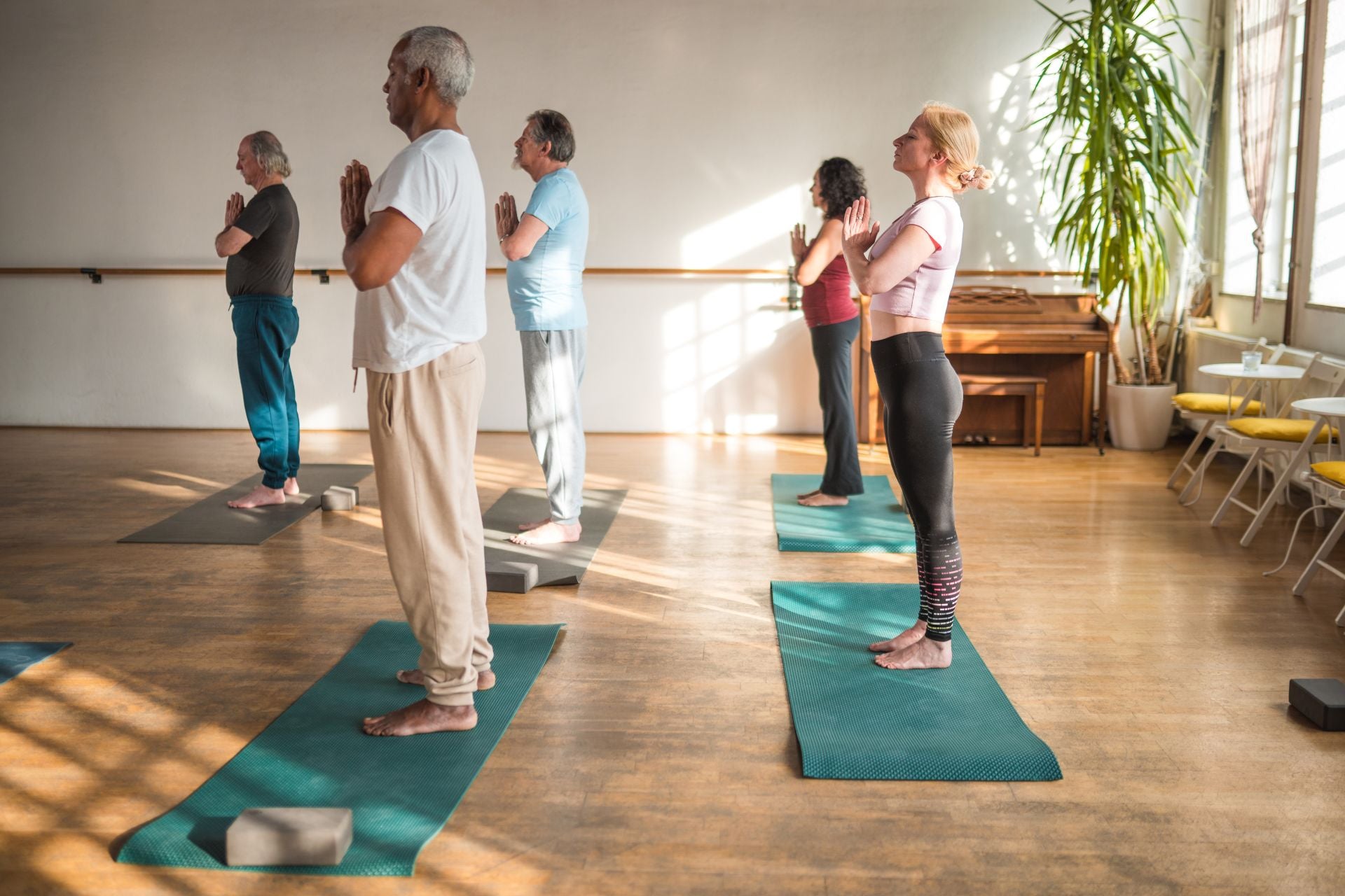 Group of men and women practicing mindfulness and meditation in a yoga studio to promote fibromyalgia relief, reduce pain, and improve well-being